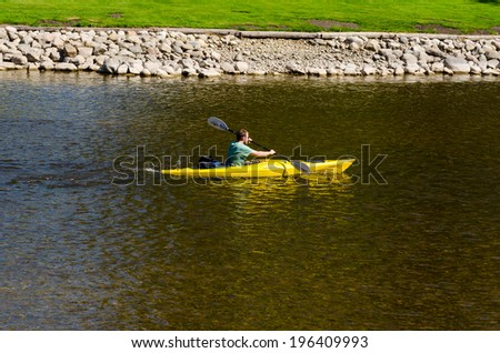 WEST MONROSE, ONTARIO - MAY 31, 2014: Young man paddling a short river kayak upstream on  a calm stretch of Grand River.