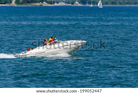 TORONTO, ONTARIO - JUNE 15, 2014: Family in a fast power boat cruising on Lake Ontario along the shoreline.