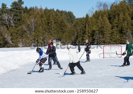 PALGRAVE, ONTARIO - MARCH 8: Outdoor enthusiasts playing a friendly game of ice hockey on an outdoor skating rink in Palgrave village in Ontario on March 8, 2015.