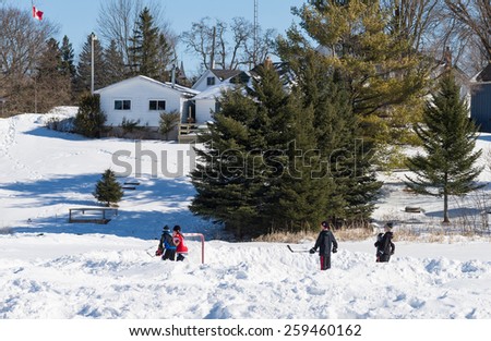 PALGRAVE, ONTARIO - MARCH 8: Children playing a game of ice hockey on a frozen pond in Palgrave, Ontario on March 8, 2015.