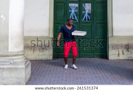 HAVANA - FEB 13:  African American man delivering a package in front of a building in Old Town of Havana on February 13, 2015.