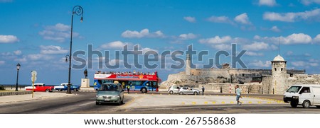 HAVANA - FEB 13: Old cars and a double-decker tour bus on Malecon boulevard in front of El Morro fort in Havana on February 13, 2015.