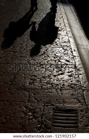 Shadow of two lovers holding hands reflected on a pavement in the sunset light
