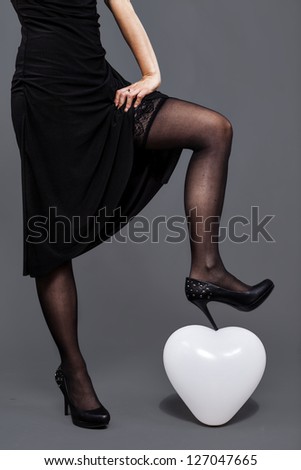 girl with lace pantyhose crushes with her shoe an heart shape balloon