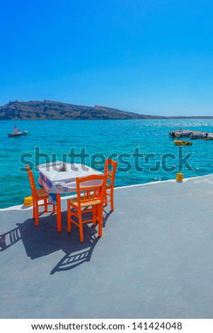 Greece Santorini island in Cyclades,  greek tavern concept by the sea with wooden chairs