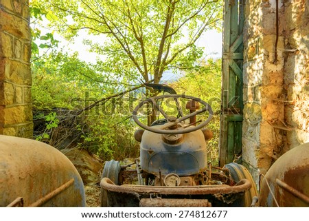 Old and abandoned Tractor in Garage at fall with leaves around