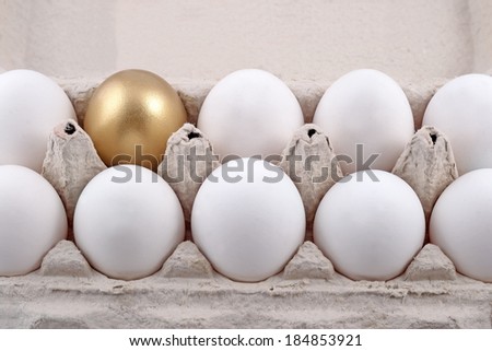 Golden egg and jast eggs in a cardboard box