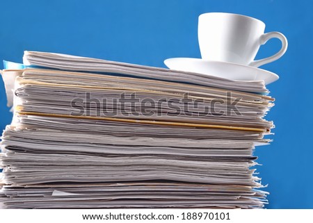 Cup on a pile of papers against a blue background