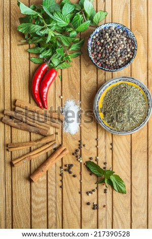 spices on cup, mint, cinnamon and pepper  on old wooden table background