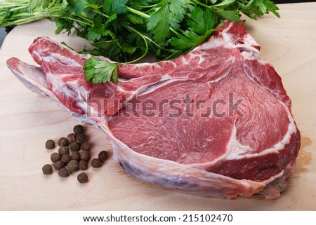a cut of uncooked beef with parsley and pepper on a chopping board