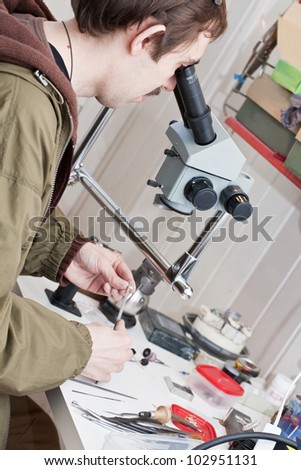 Male jeweller is working at jeweller\'s workshop