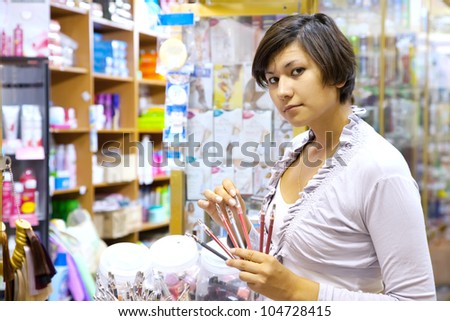young woman chooses the cosmetic pencil at cosmetics  shop