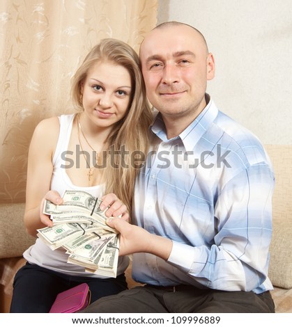 Happy young family with many US dollars  in home