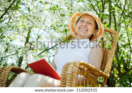 Relaxing  mature woman  reading book in bloom garden