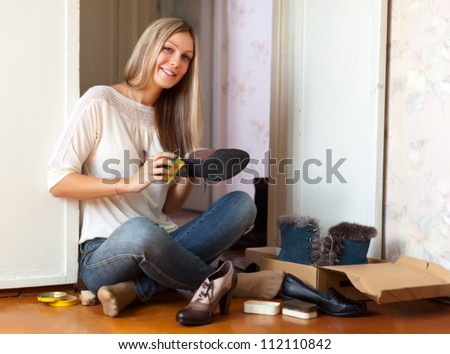 Woman sits on floor and cleans shoes