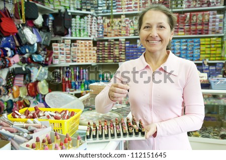 Mature woman  chooses   lipstick at cosmetics  shop