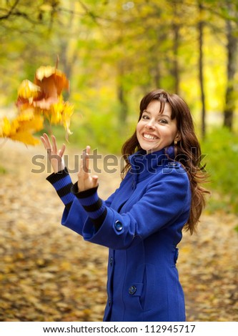 Girl in blue coat throw up maple leaves