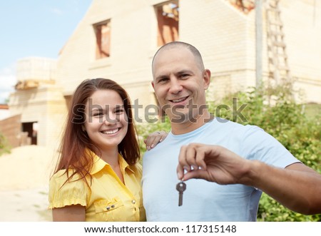 Happy couple with key against building new brick house   outdoor