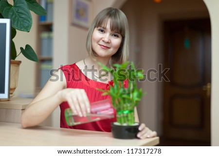 Young woman with lucky bamboo plant at her home