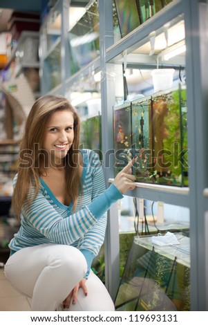 Woman chooses  fish tank in pet-shop