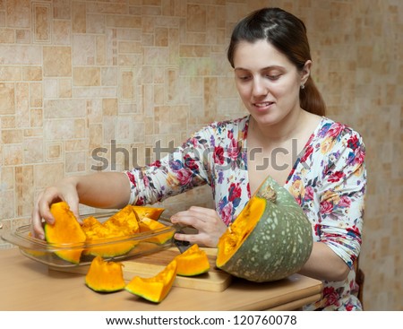Woman cooks pumpkin in  kitchen