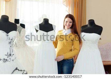 Smiling woman chooses  wedding dress in bridal salon