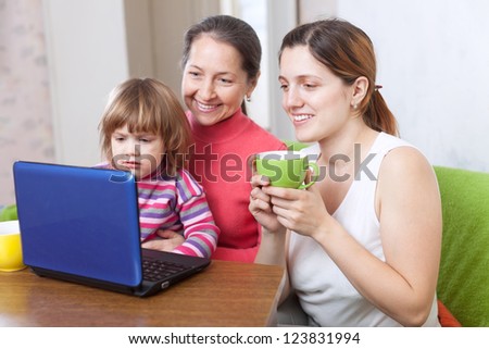 Happy women  of three generations looks the netbook in home interior