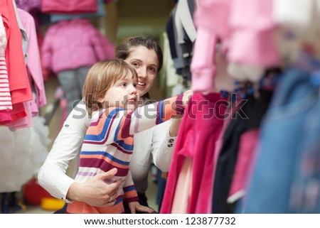 Happy family  chooses wear at fashionable shop. Focus on girl