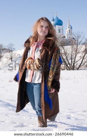girl in russian traditional clothes with round cracknel against  Russian landscape