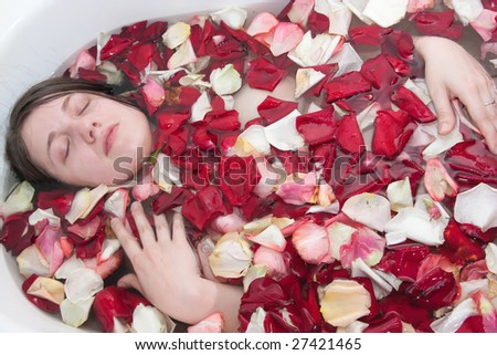 Young woman enjoys the rose-leaf in the bathtub.