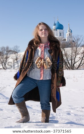 girl in russian traditional clothes with round cracknel against  Russian landscape