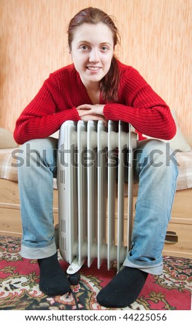 young smiling girl is sitting by a oil heater