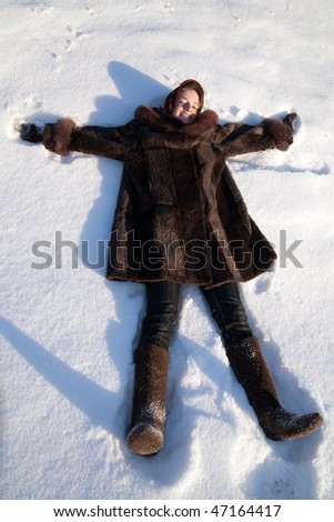 Girl in  fur coat  making snow angels