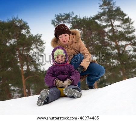 Young girl riding in a city park with a snow slide.