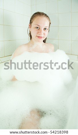 Young girl enjoys the bath-foam in the bathtub