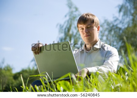 Handsome man  working on laptop in the meadow