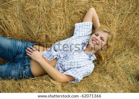 Pretty girl in checked shirt resting on hay bale