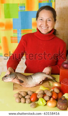 Mature woman is cooking red  fish  in kitchen. One of the stages of preparation of  stuffed fish.  See series