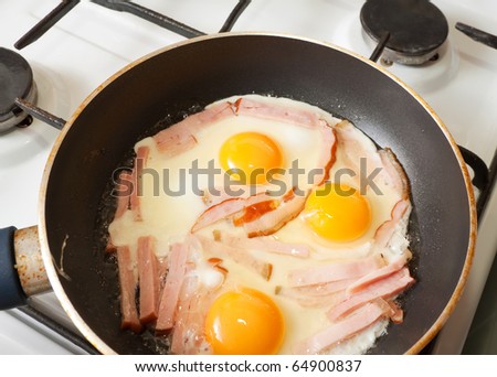 eggs and bacon on hot skillet. One of the stages of preparation of bacon and eggs.  See series