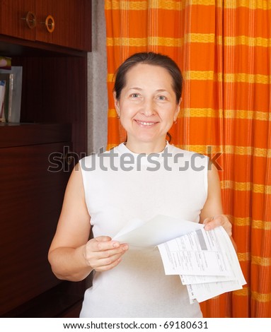 Smiling mature woman with utility bills  at her home