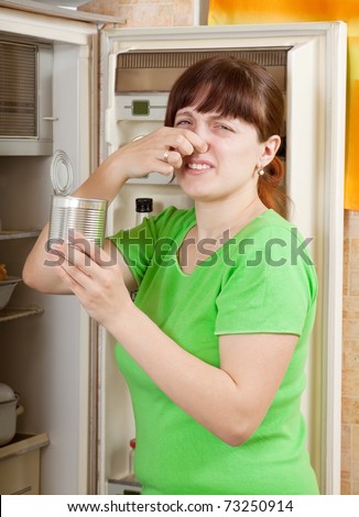 woman  holding her nose because of bad smell near fridge at home