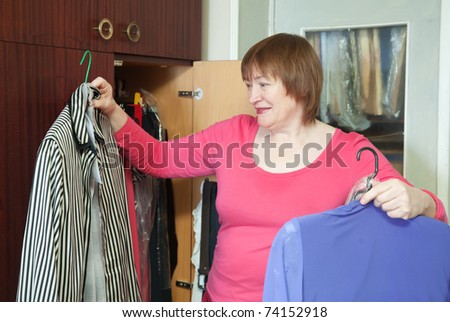 Mature woman at wardrobe. She thinking what get dressed.