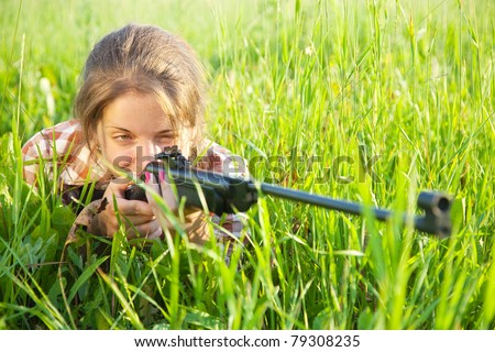 girl  aiming a pneumatic air rifle  in grass meadow