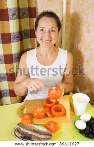 Woman cooking farci tomato in her kitchen. See in series stages of cooking of farci tomato salad