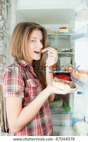 Teenager girl eating  meat from  refrigerator  at home
