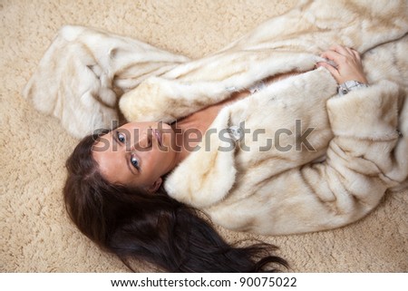 Sexy woman in fur coat laying over  rug