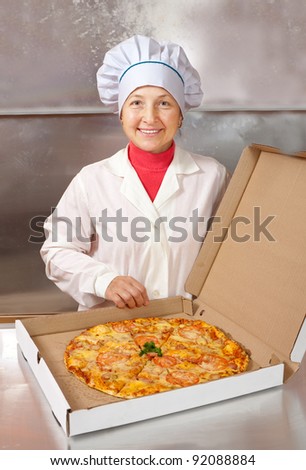 female cook with cooked pizza in box