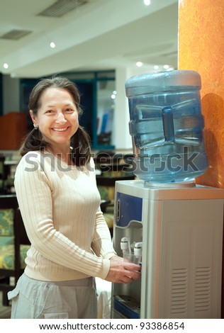 Woman pours   water from water cooler