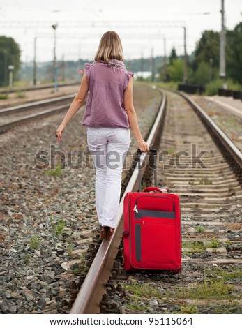 Rear view of woman with luggage walking on rail