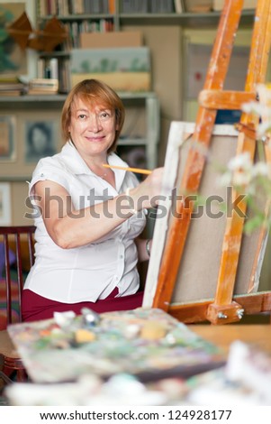 woman artist paints  on canvas in studio